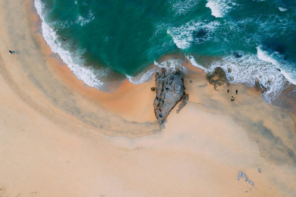 Aerial shot of a serene beach with turquoise waters and gentle waves, perfect for a summer escape.